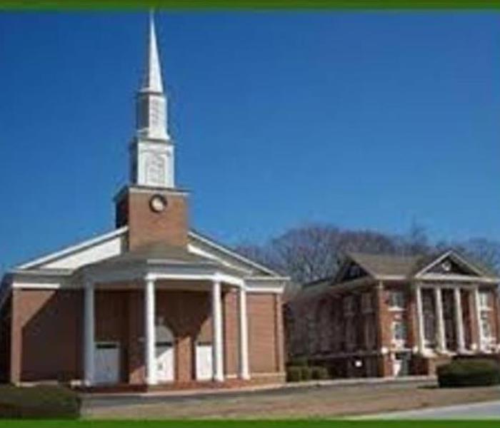 2 large brick buildings with tall columns in front, building on left has steeple.