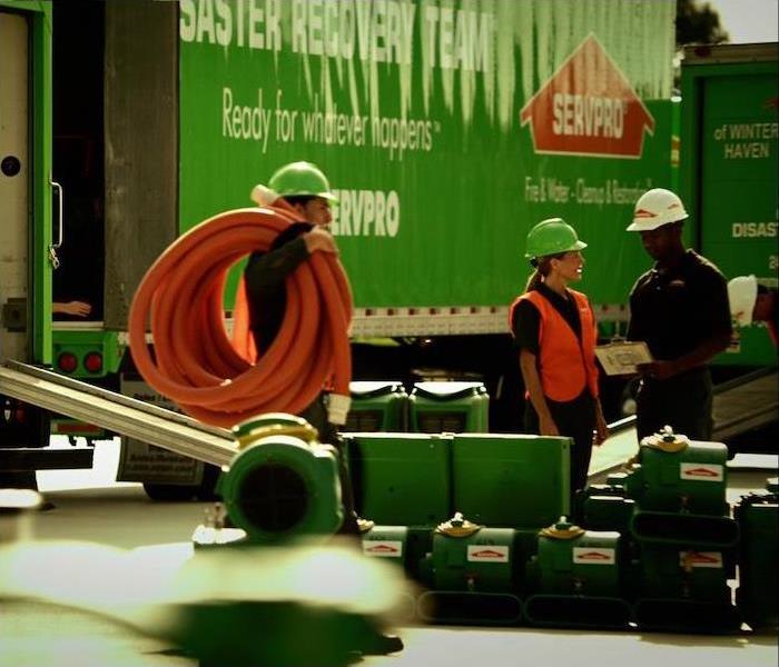  img src =”team” alt = " group of 3 SERVPRO reps standing near a green semi truck at a work site ” >