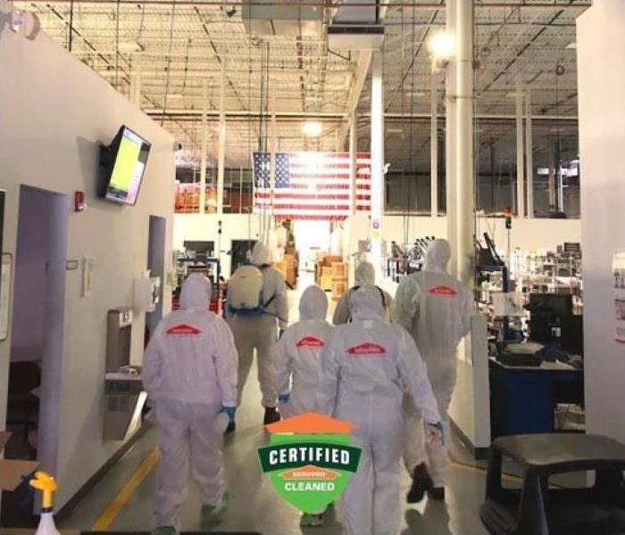 "a crew of SERVPRO employees in PPE gear walking inside commercial building